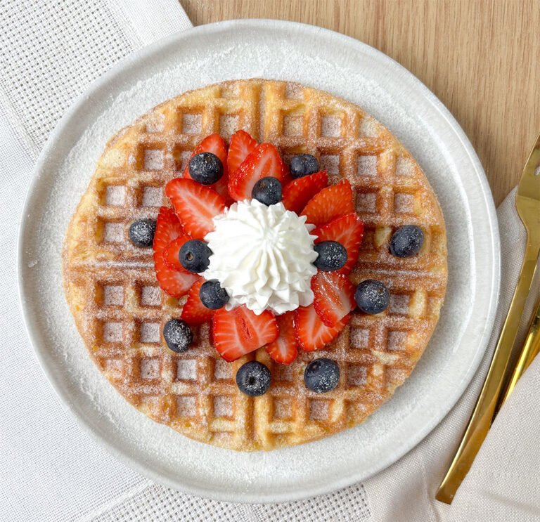 Visão do waffle pronto com cobertura de chantilly e frutas frescas